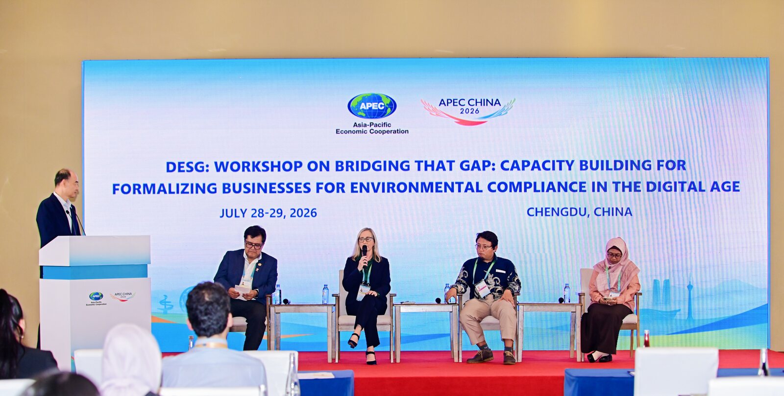 Day one panel on stage with four speakers and a moderator